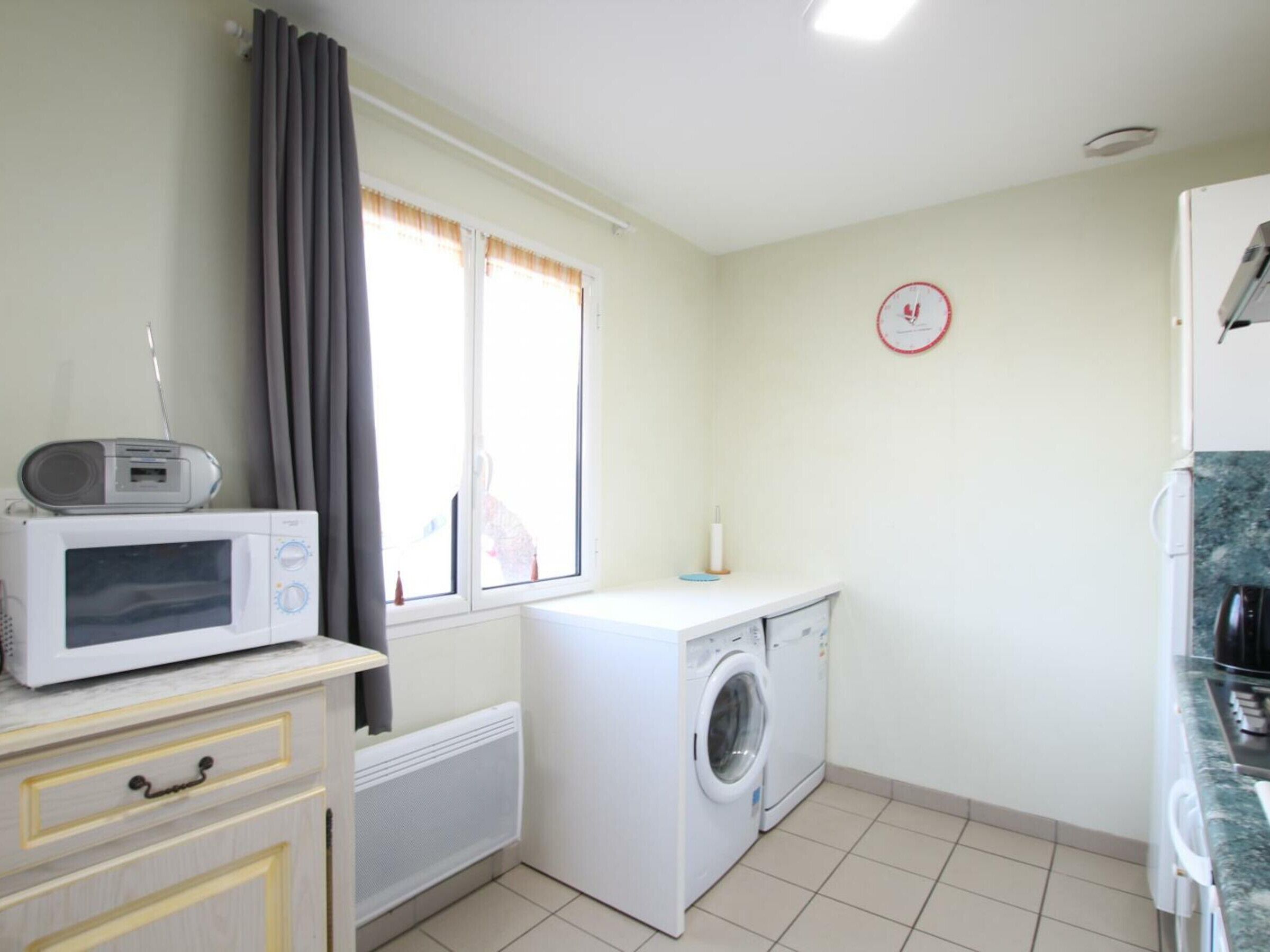 A compact kitchen with a microwave, a washing machine, and a small countertop.