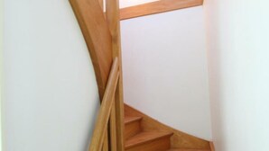 Eine hölzerne Wendeltreppe mit Handlauf, die zu einer oberen Etage führt.