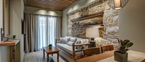 A cozy living room with a stone wall, wooden ceiling, and a sofa with cushions.