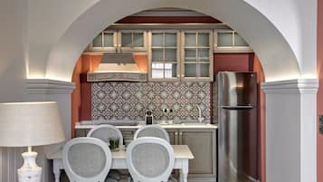 Una cocina con un arco de entrada, salpicadero decorado, electrodomésticos de acero inoxidable y una mesa de comedor con sillas.