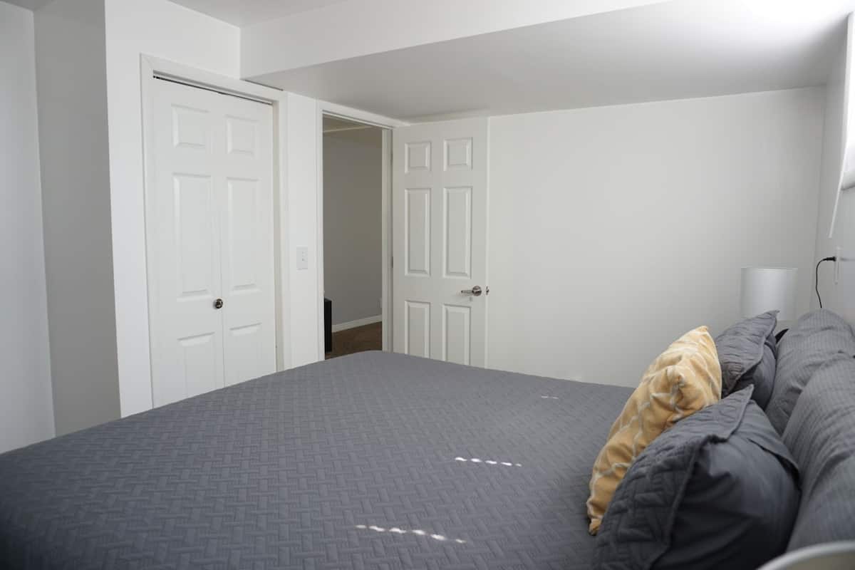 A bedroom with a bed, two white doors, and a bedside lamp.