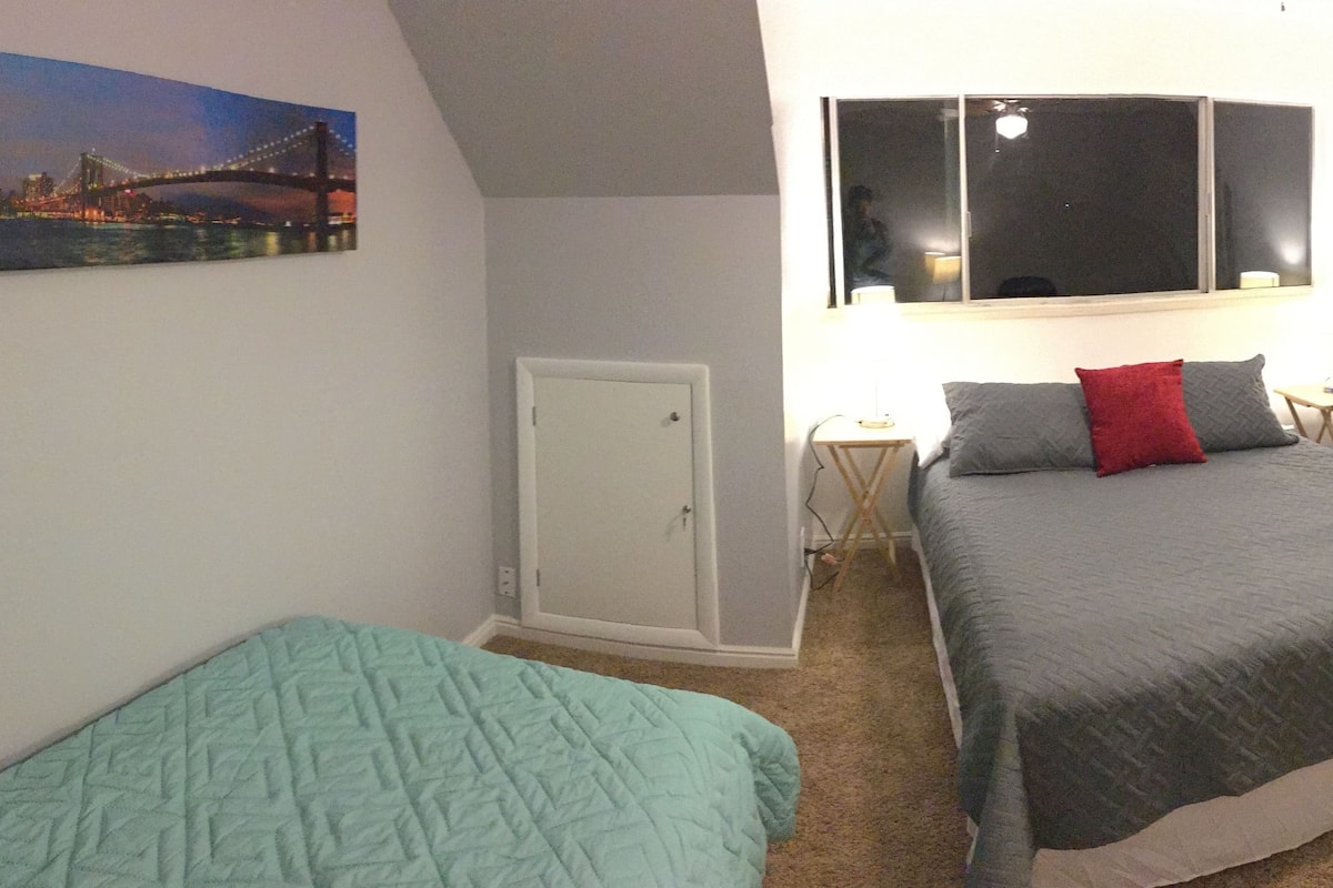 A bedroom with a bed, a desk, a chair, a wardrobe, and a door.