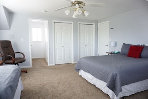A bedroom with a bed, a chair, and two doors.