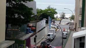 A narrow street with parked cars and buildings on both sides. - Apartamento Copacabana Vista mar (Rio de Janeiro)