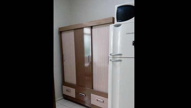 A room with a wardrobe, a white refrigerator, and a tiled floor. - Apartamento Copacabana Vista mar (Rio de Janeiro)