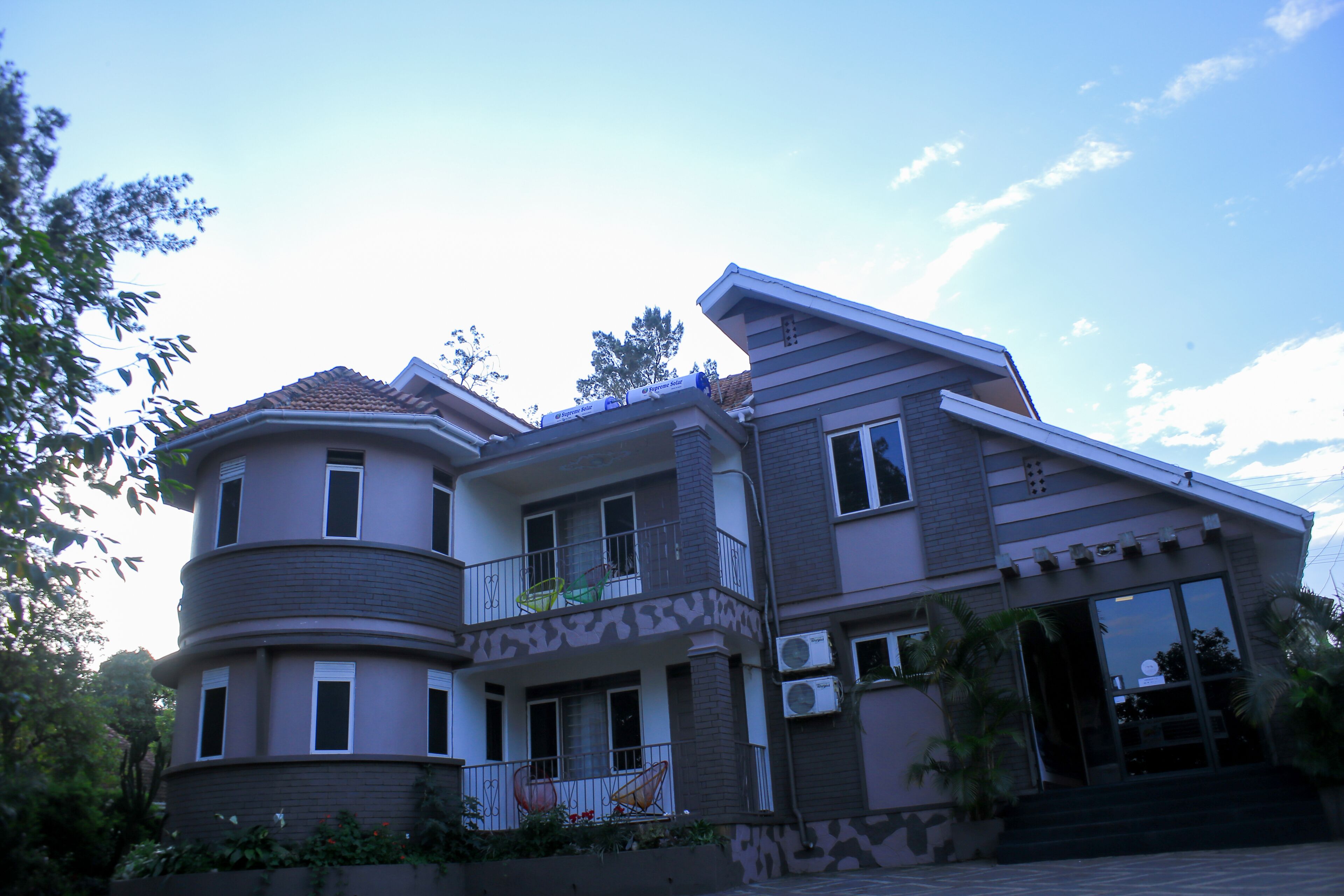 A multi-story residential building with a balcony, air conditioning units, and a gated entrance.