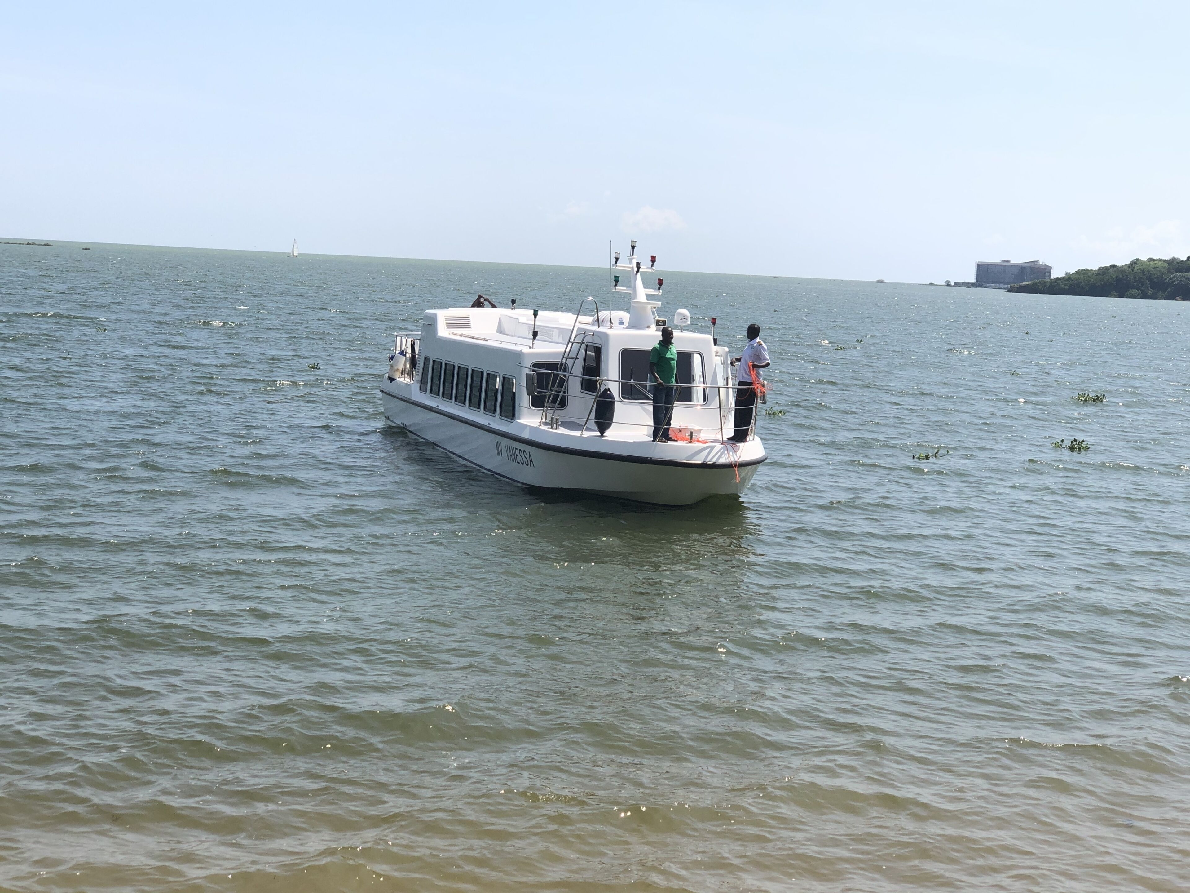 Een boot met twee personen op het dek, een witte kajuit en een heldere lucht.