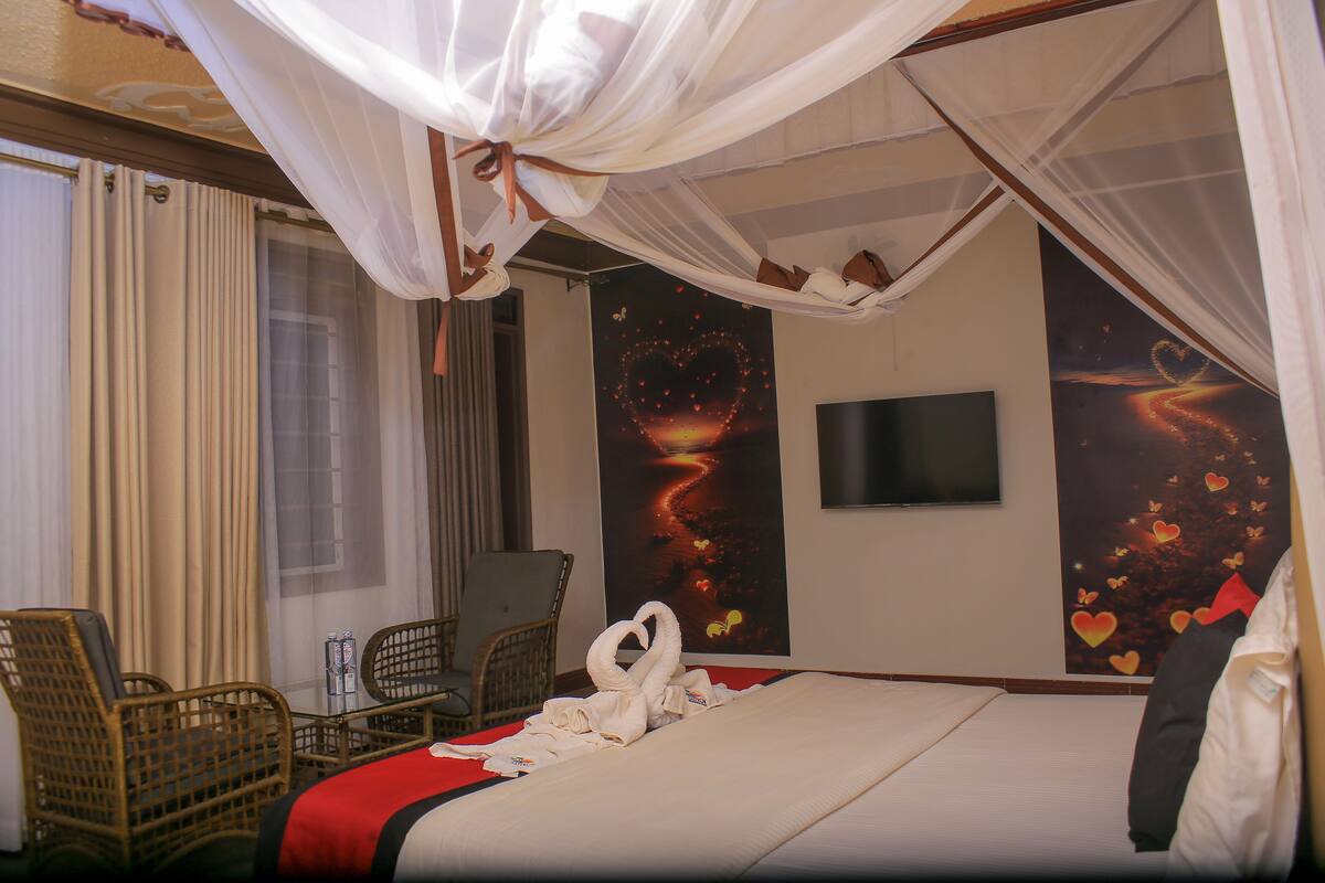 Quarto de hotel com cama, televisão, escrivaninha e cadeira.