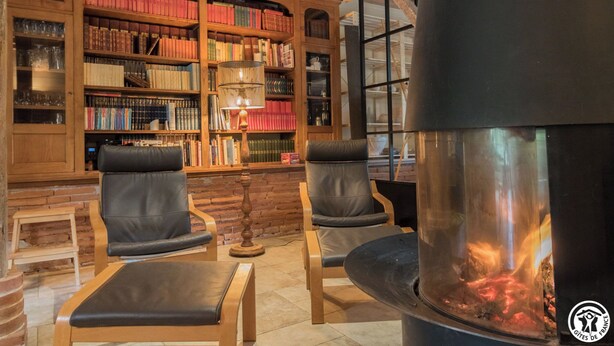 Una biblioteca accogliente con poltrone in pelle, un camino e scaffali pieni di libri.