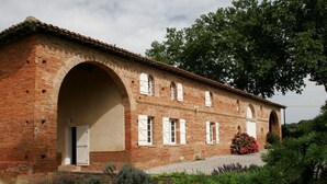 Un edificio in mattoni dal design tradizionale, con porte e finestre ad arco, immerso nel verde.