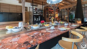 Una cucina moderna con un piano di lavoro in marmo, travi in legno e un'isola centrale con prodotti per la colazione.