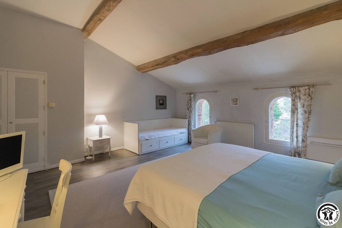 Un dormitorio con cama, escritorio, silla, cómoda y ventana con cortinas.