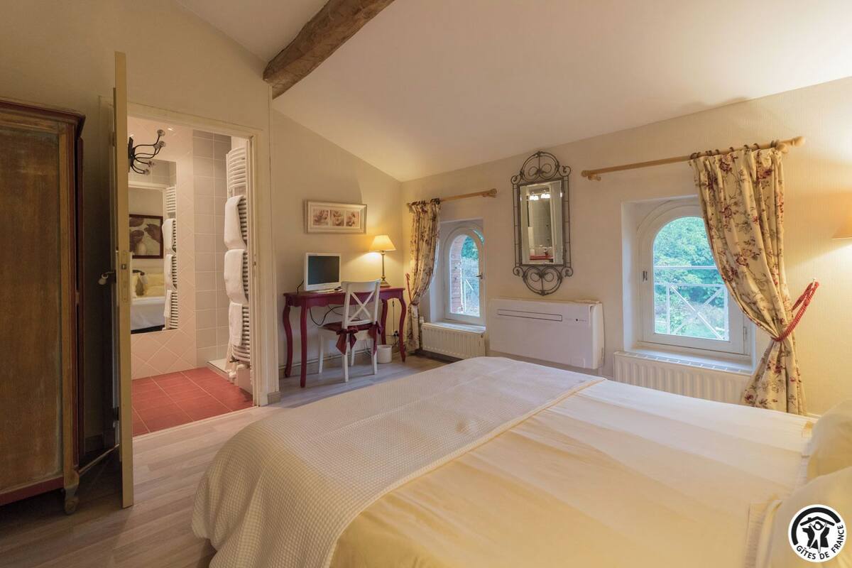 Un dormitorio con una cama, un escritorio con computadora, una ventana con cortinas y un radiador.