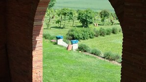 Un arco in mattoni con vista su un giardino curato e un edificio in lontananza.