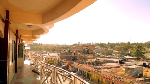 A balcony with a view of a cityscape, including buildings and a clear sky. - Olorropil Hotel (Narok)