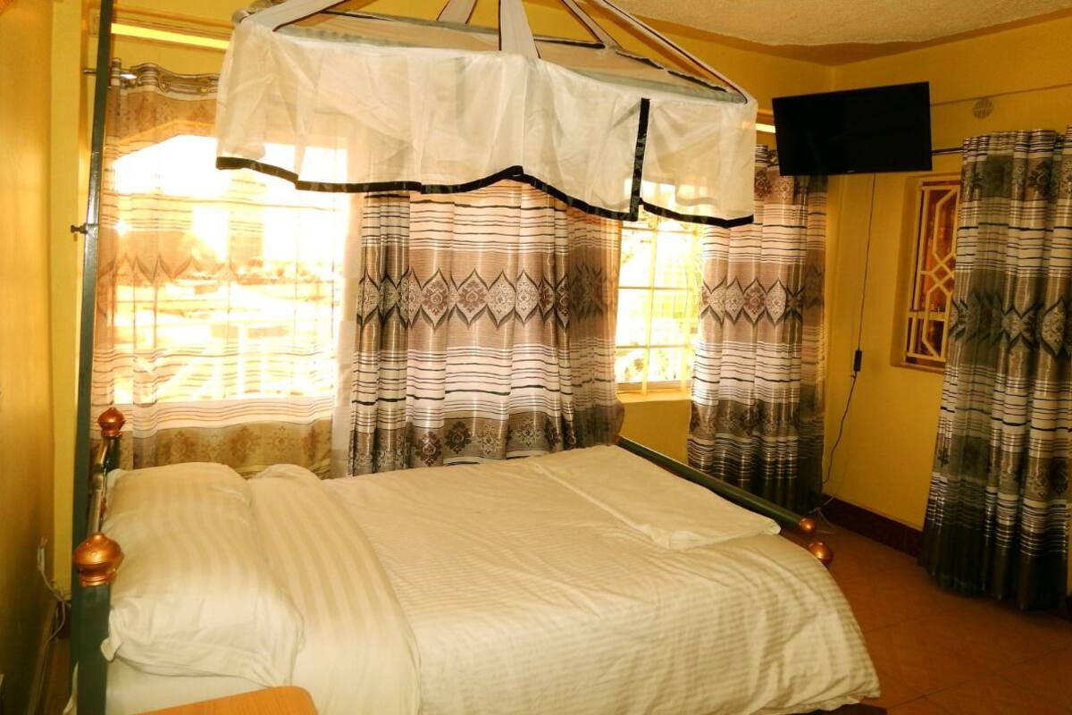 A room with a bed, curtains, a television, and a window.