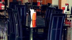A dining area with black upholstered chairs and a glass table. - Olorropil Hotel (Narok)