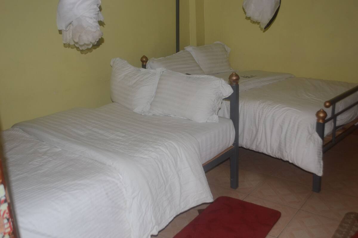 A single bed with a wooden frame and white bedding in a room with yellow walls.