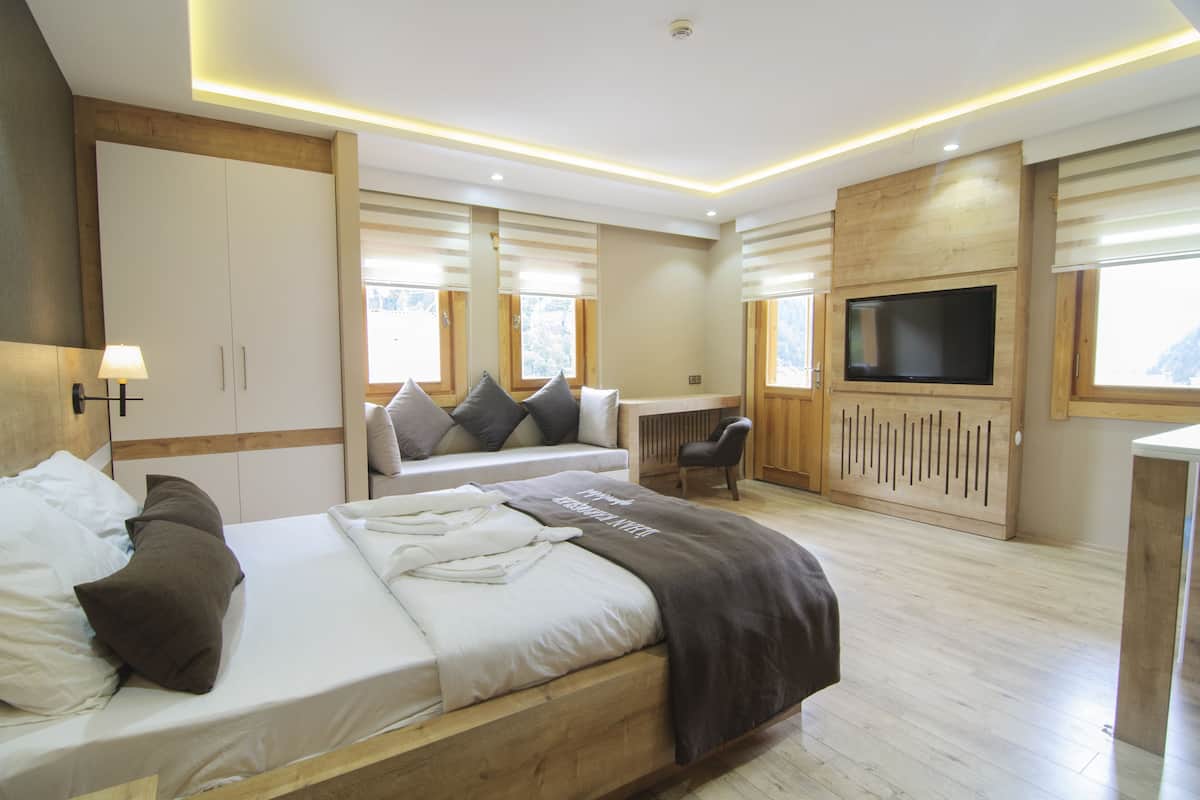 Ein modernes Schlafzimmer mit einem großen Bett, Nachttischen, einem Fernseher und einem Schreibtisch.