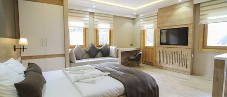 A modern bedroom with a large bed, bedside tables, a TV, and a desk.
