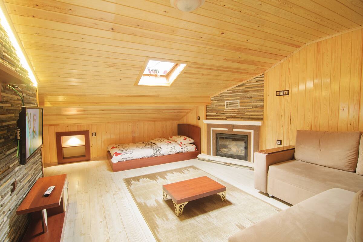 Ein gemütliches Holzhaus mit Bett, Sofa und Kamin.