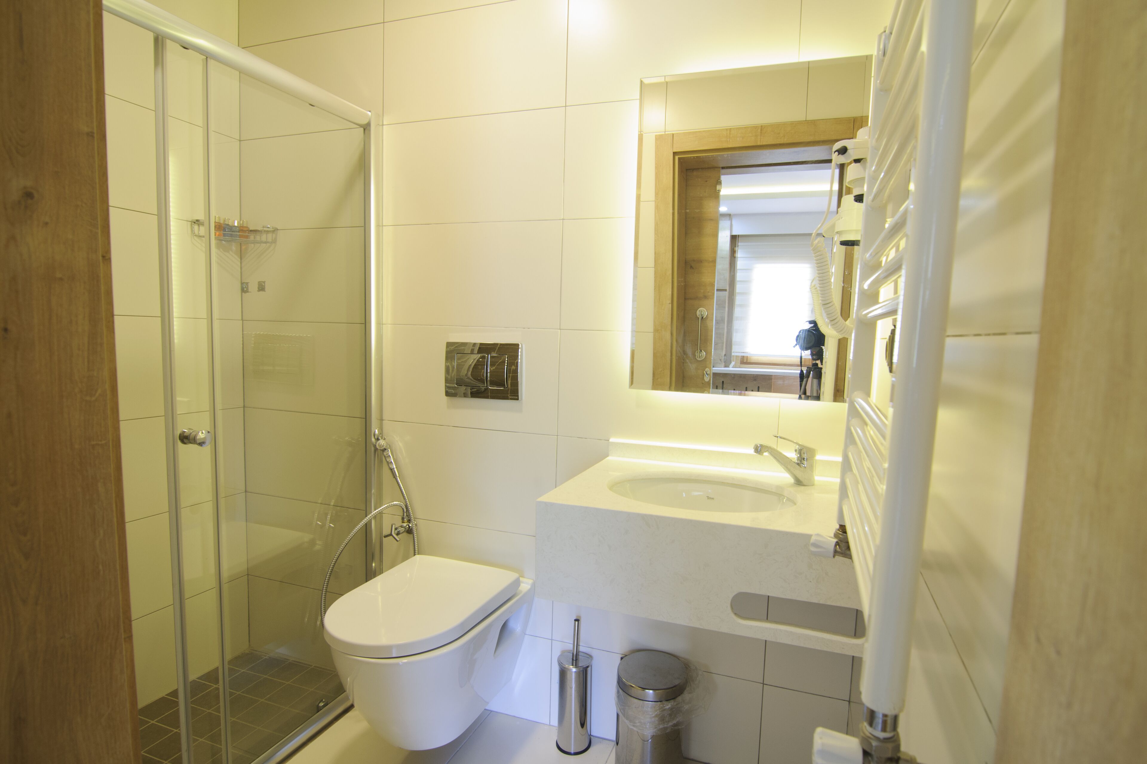Ein modernes Badezimmer mit einer Duschkabine aus Glas, einer weißen Toilette und einem Waschbecken mit Spiegel darüber.
