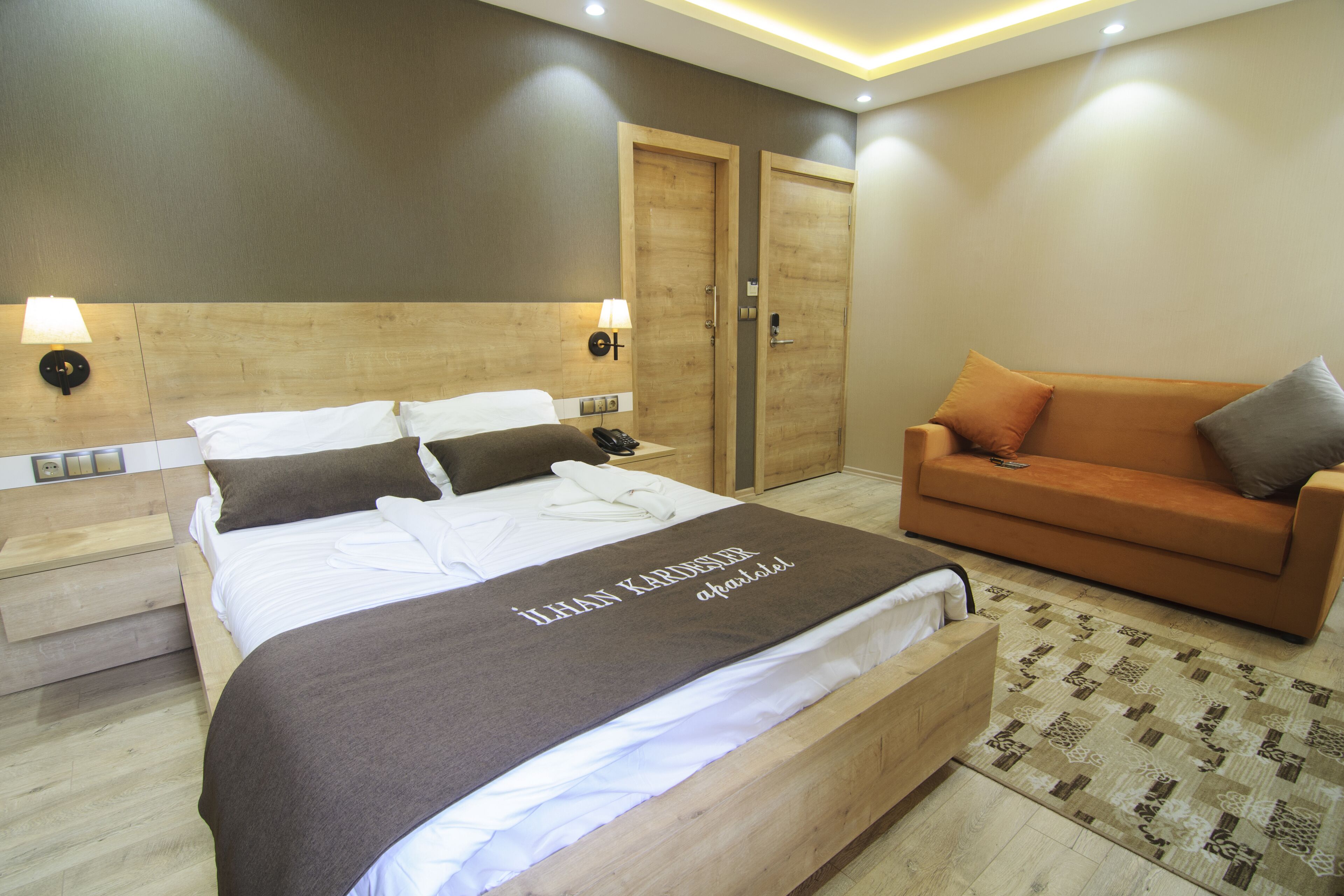 Una habitación de hotel moderna con una cama grande, un sofá y un cabecero de madera.