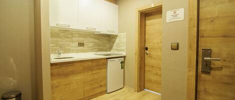 A compact kitchen with wooden cabinets, a white countertop, and a small dishwasher.