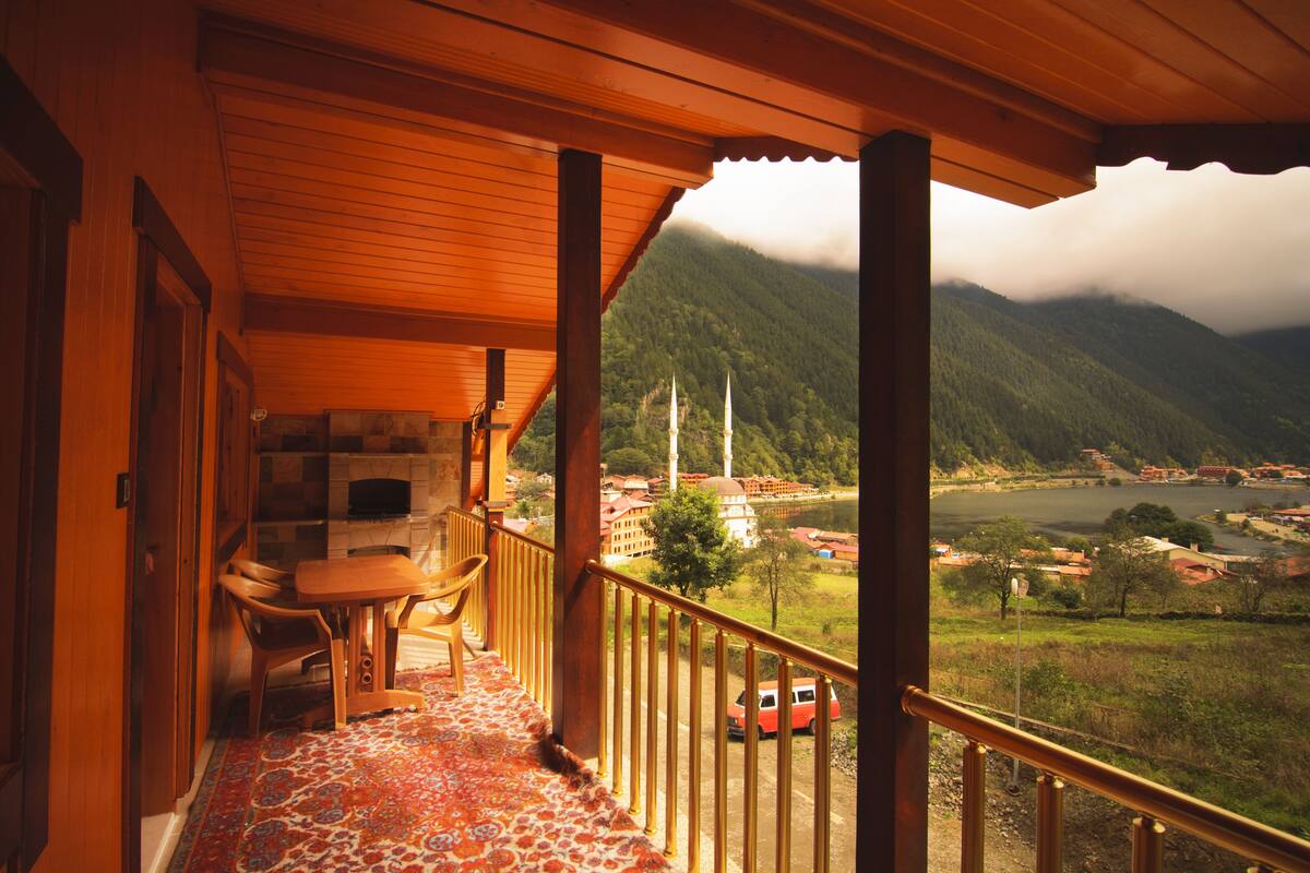 Ein Holzbalkon mit Blick auf eine gebirgige Landschaft und einen Fluss.