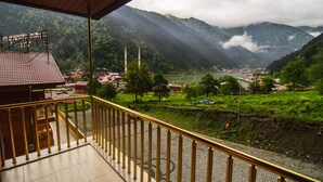 Un balcon offrant une vue sur un paysage montagneux, une mosquée et une rivière.