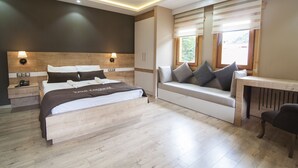 Une chambre moderne avec un grand lit, des tables de chevet, un bureau et une fenêtre avec des stores.