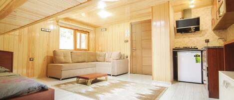 Una cabaña de madera con sala de estar, cocina y un dormitorio.