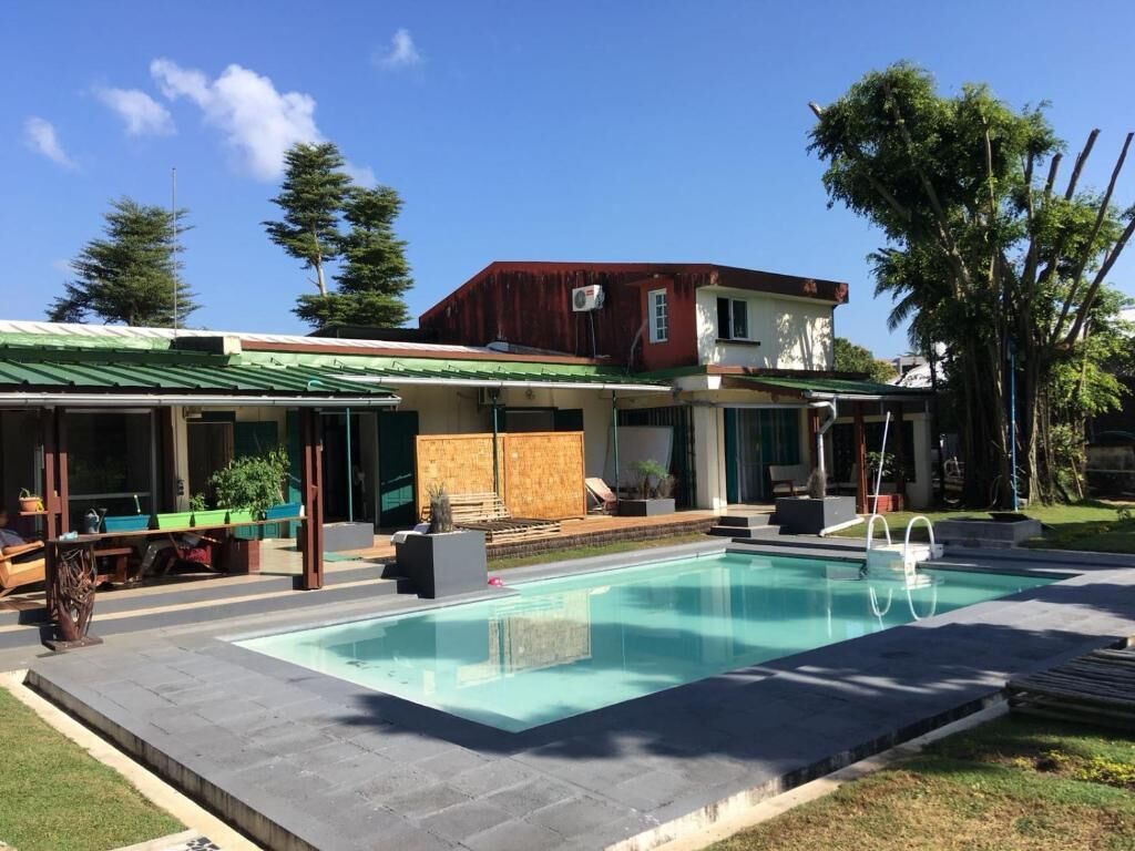Una casa moderna con piscina, un porche cubierto y un jardín.
