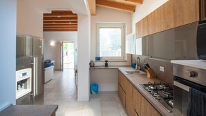 A modern kitchen with wooden cabinets, a stainless steel refrigerator, and a gas stove. - Gate To Verona (Verona)