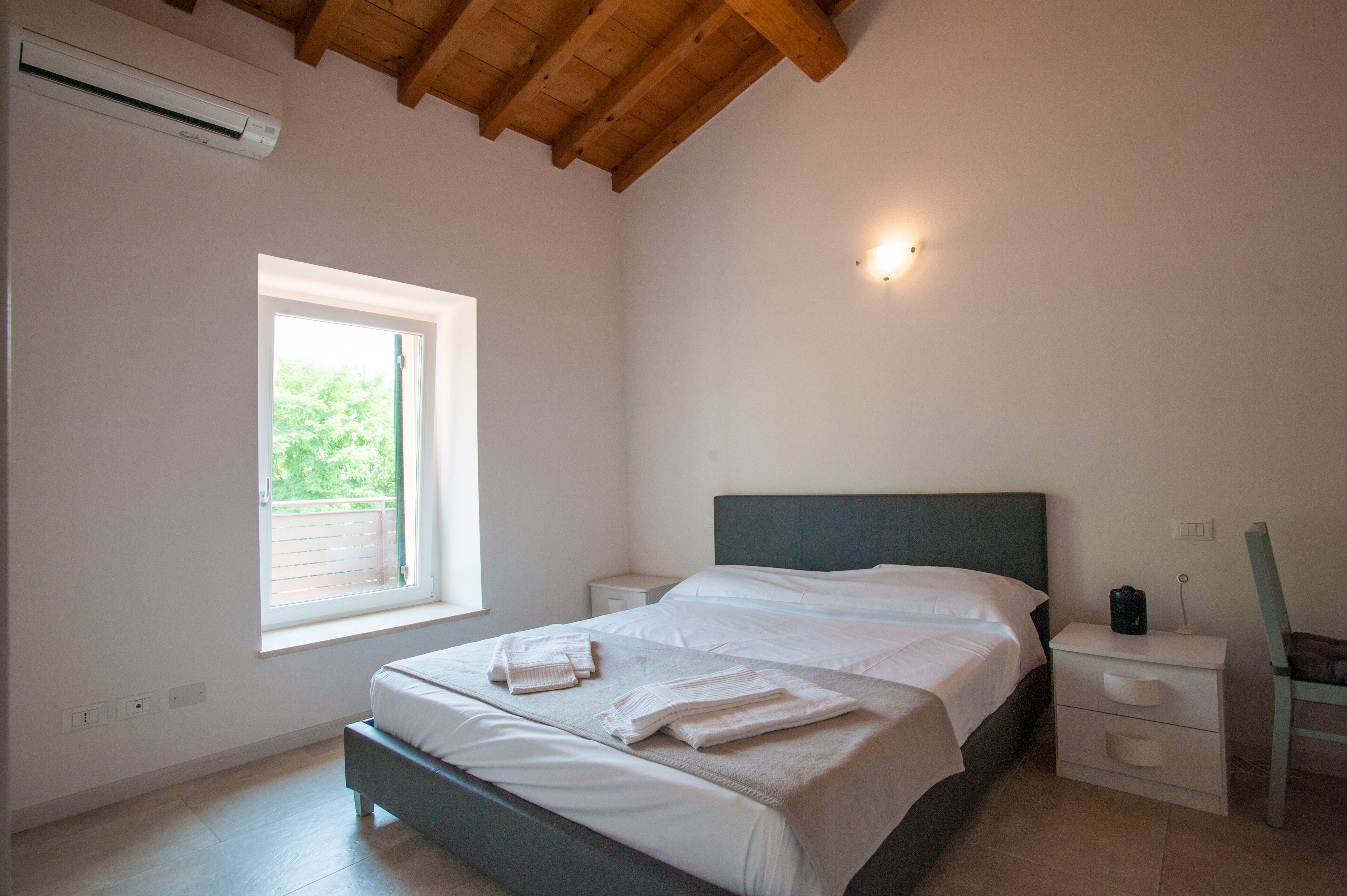 Een slaapkamer met een bed, nachtkastje en een raam.