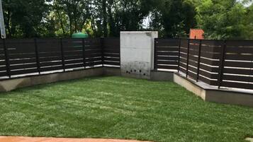 A fenced backyard with a paved patio area and a grassy lawn.
