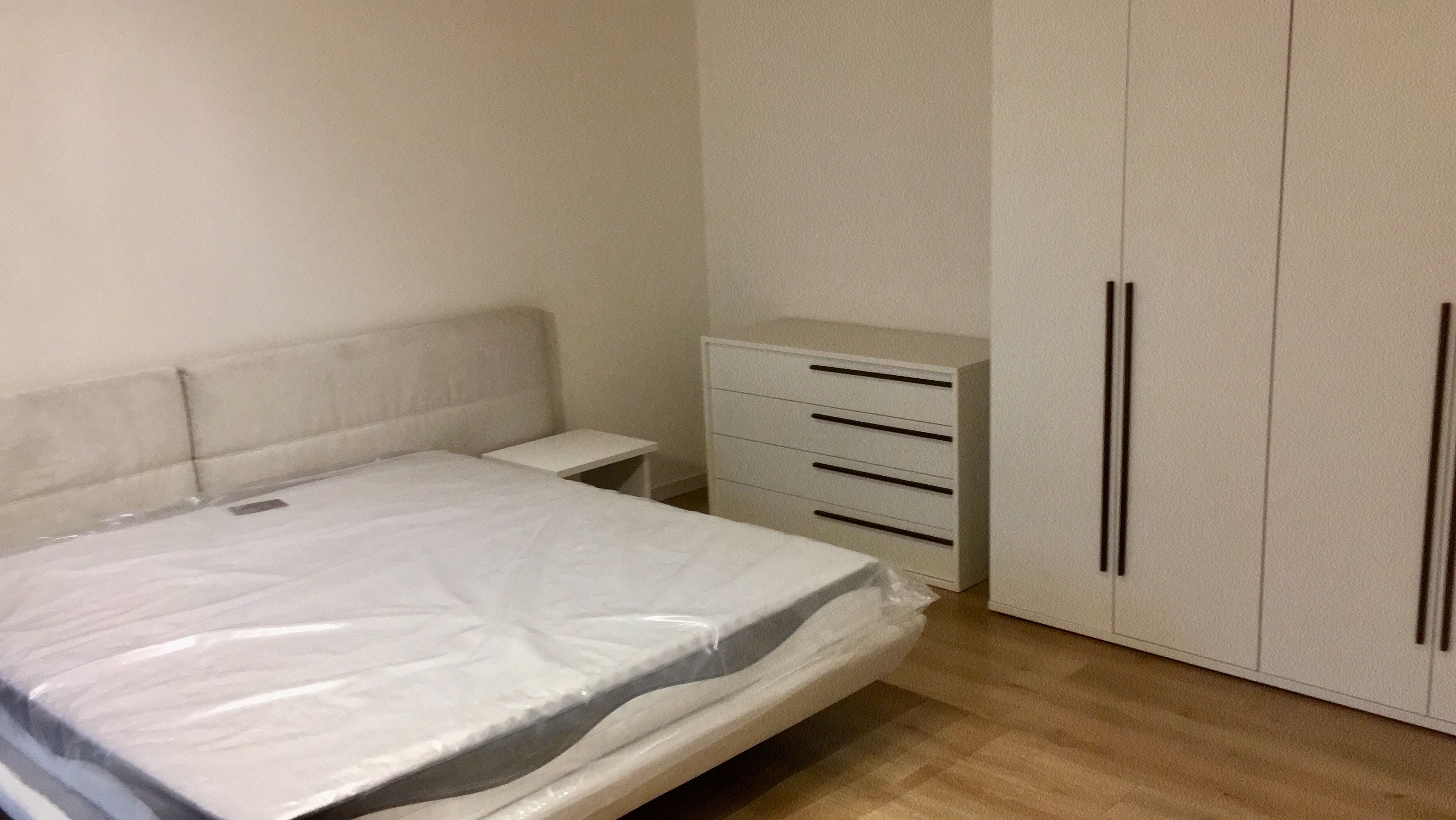 Ein Schlafzimmer mit Bett, Nachttisch, Kommode und Kleiderschrank.
