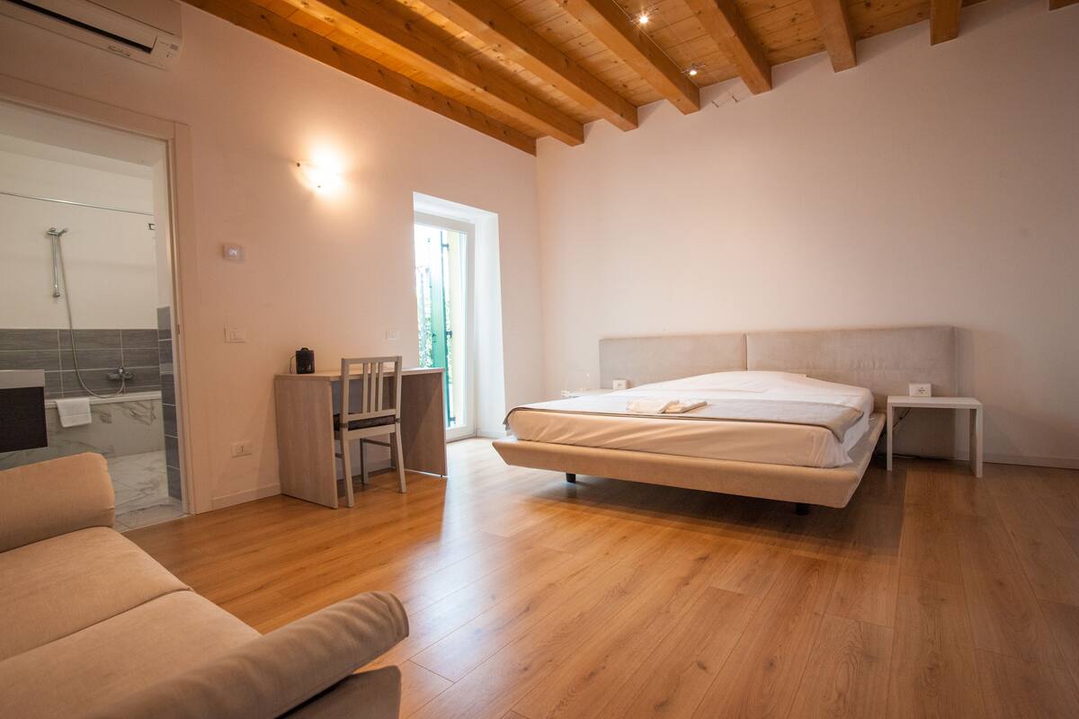 Ein Schlafzimmer mit einem großen Bett, Holzboden, einem Schreibtisch und einem Stuhl.
