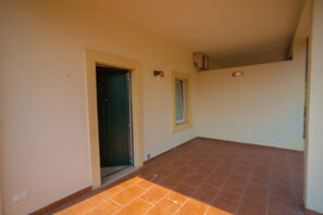 Una habitación con piso de baldosas, una puerta y un ventanal.