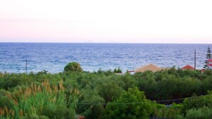 A view of a coastal area with a fence, greenery, and a body of water in the background. - 7 Seaview Studios 150 meters from the Sea + 6000 sq.m2 garden (14 to 19 persons) (Zakynthos)