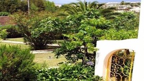 A garden with various plants and a white wall with a decorative gate. - sunny ap. for 2-6 people, exclusive 1a location directly on the beach by the sea (Ferragudo)