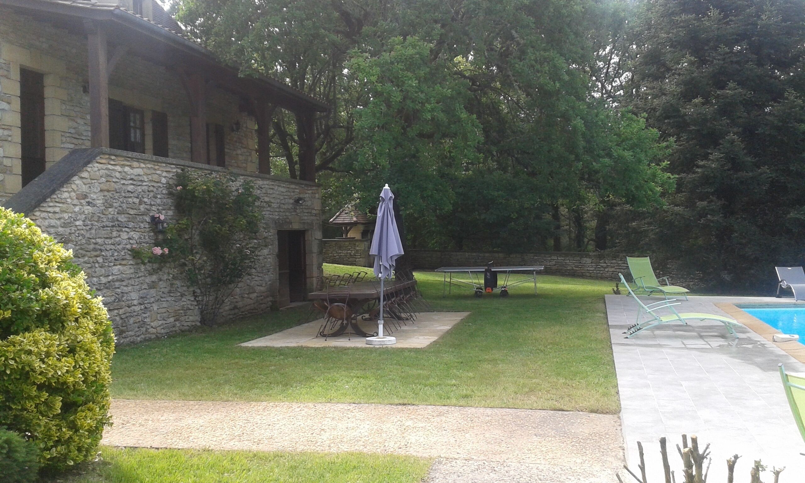 Un bâtiment en pierre doté d’une terrasse, d’une piscine et d’un court de tennis.