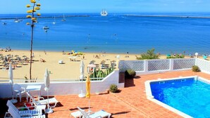 Vista de una playa con piscina y sillas de descanso.