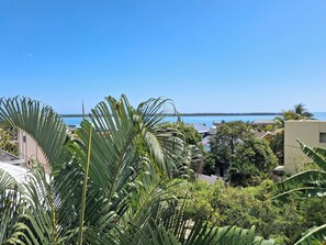 A tropical landscape with dense foliage, a clear blue sky, and a distant view of a body of water. - La Gaulette Grand Loft, Pool & Panoramic Sea View  (La Gaulette)