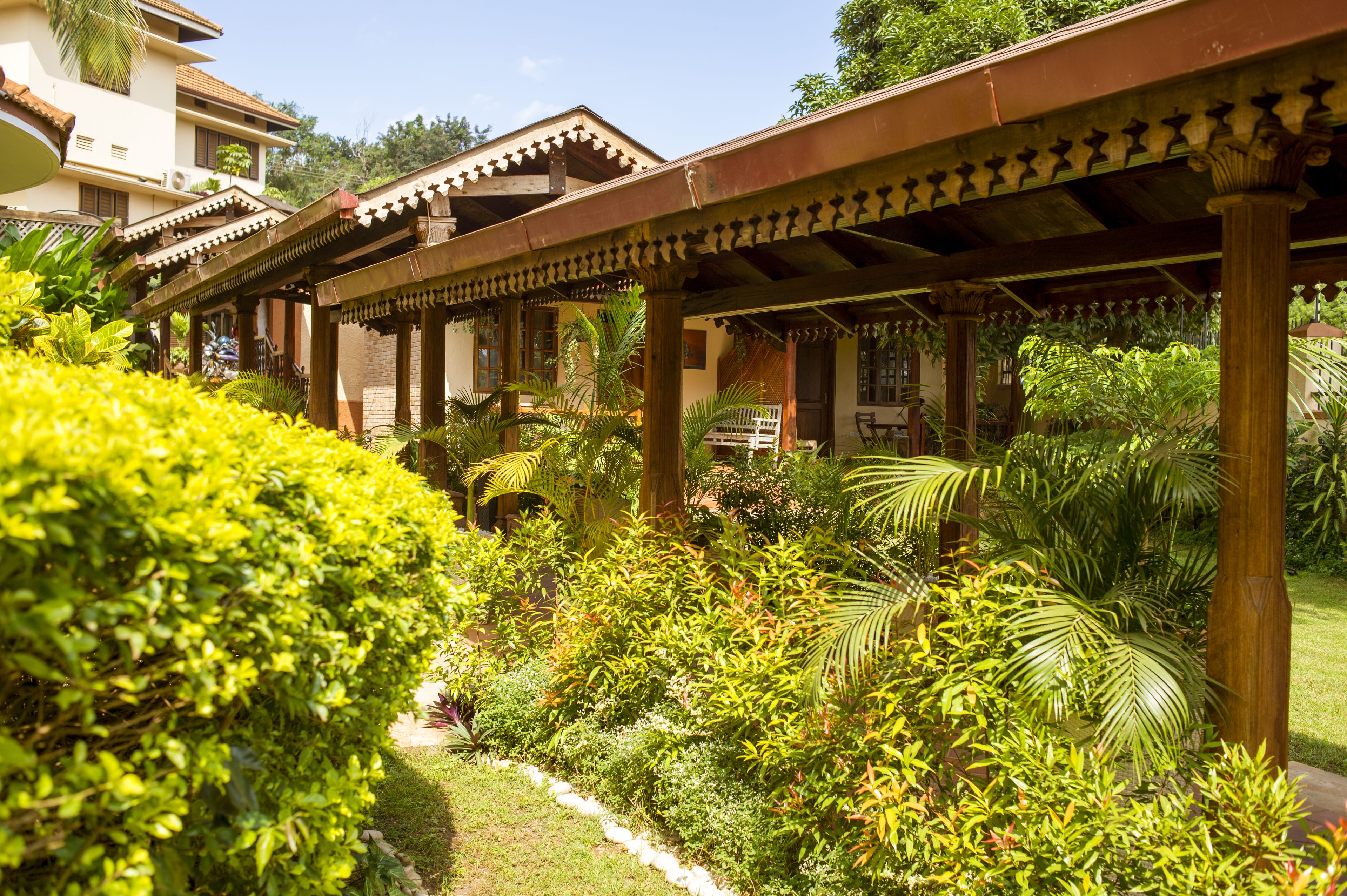 A covered outdoor area with wooden columns and a garden with various plants.