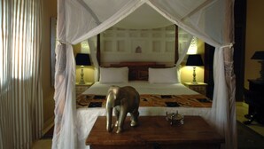 A bed with a canopy, two bedside lamps, and a decorative elephant figurine on the nightstand. - Villa Kololo Guest House (Kampala)