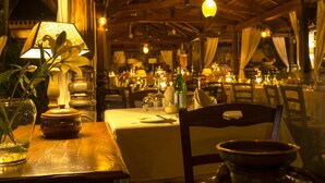 A restaurant interior with wooden tables, chairs, and hanging lights. - Villa Kololo Guest House (Kampala)
