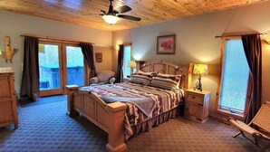 A bedroom with a wooden bed, a chair, a nightstand, and a window with curtains.