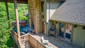 A wooden deck with outdoor furniture, a stone pillar, and a hot tub.