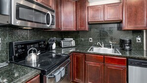 A kitchen with stainless steel appliances, granite countertops, and wooden cabinets.